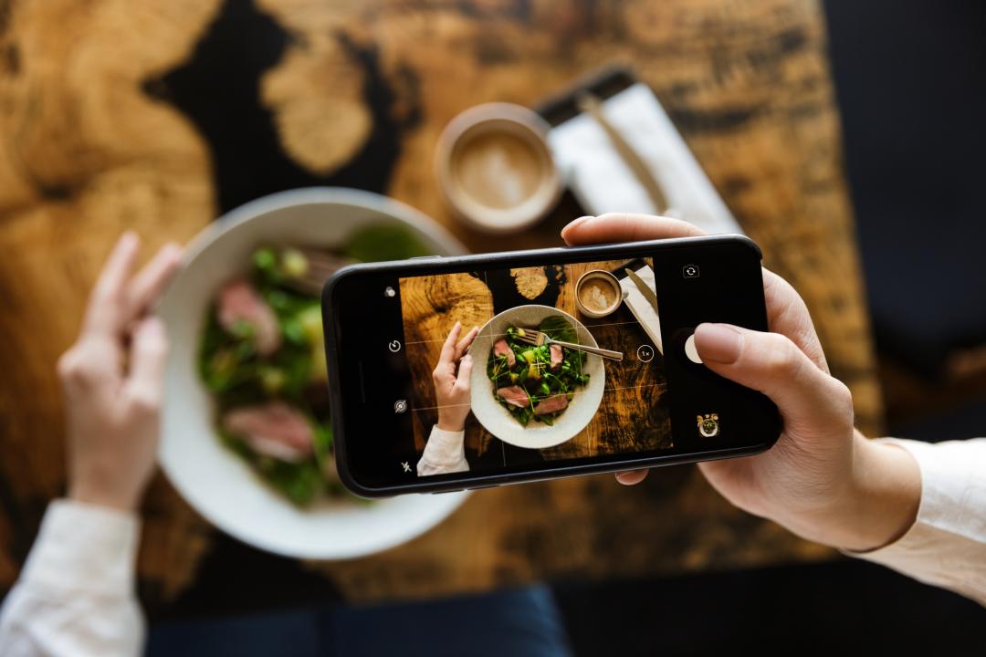 A person taking photo of a bowl of food